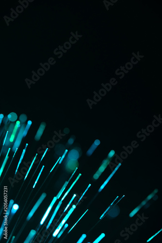 Fotografie Vibrant turquoise fiber optic lines flare up diagonally from corner against black backdrop