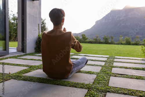 Concrete pavers with grass are shaping patio by glass sliding door, sun casting glow on ridge