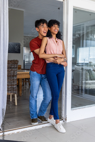 Obraz na plátně Diverse couple entering through sliding door after returning home, man hugging w