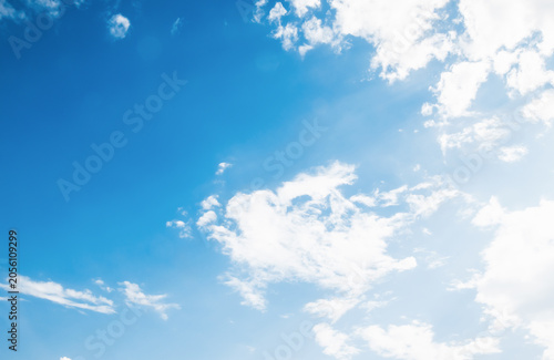 the sky is clear blue with fluffy white clouds, the sky is very bright, and the sun shines.