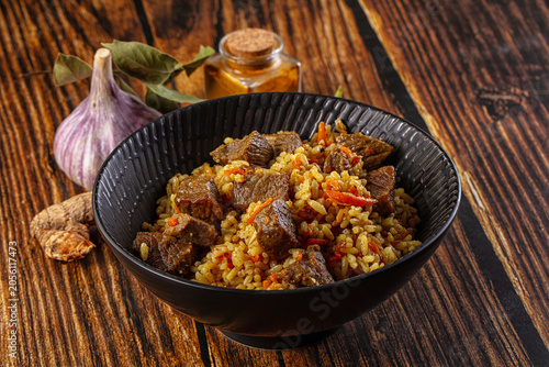 Asian traditional pilaf with beef, garlic, and spices on rustic wood