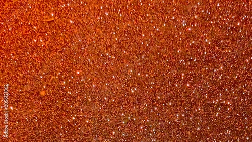 Sparkling orange glitter background, with varying textures, and light reflections