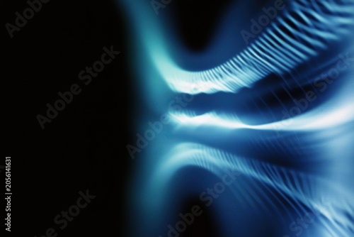Abstract blue light waves flowing over dark background surface