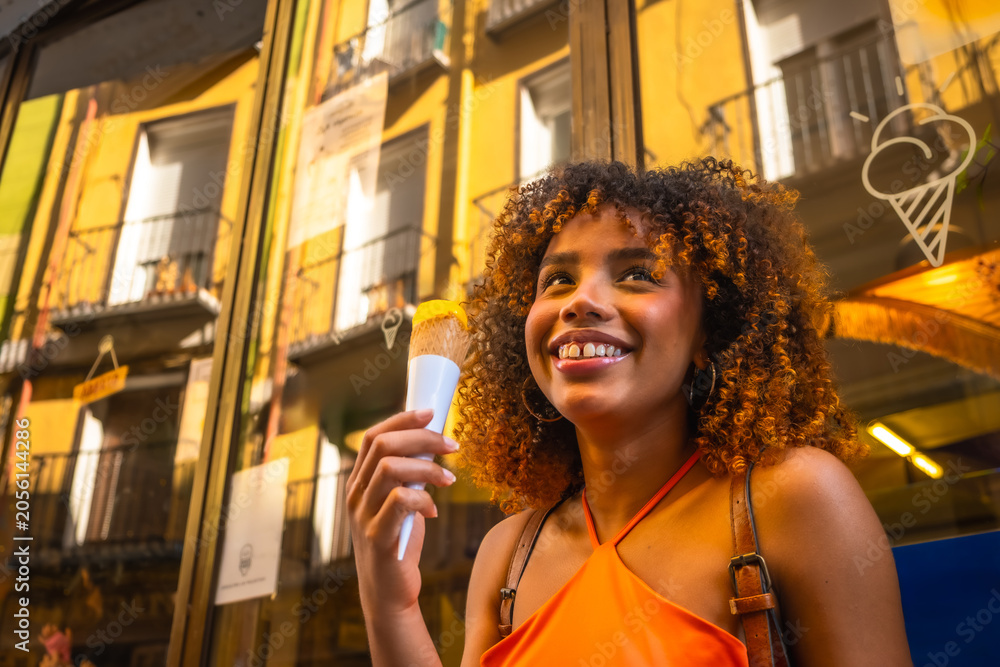Obraz premium Happy young woman enjoying ice cream on city street