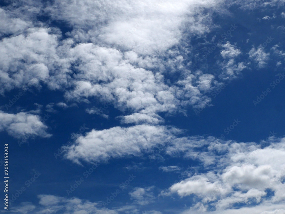Fototapeta premium A bright blue sky background with beautiful clouds; a bottom-down, wide-angle view.