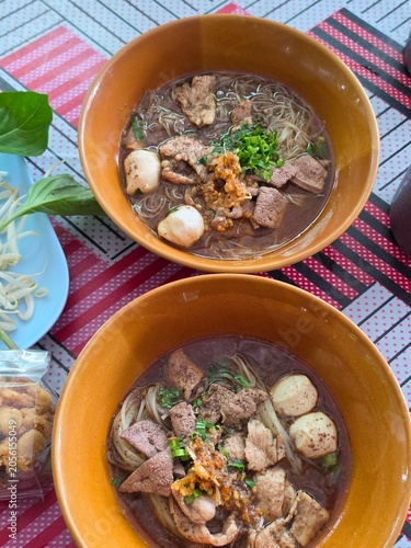 The closed up of Thai noodles. Asian noodle soup with beef meatball with fresh vegetable on wood table. 