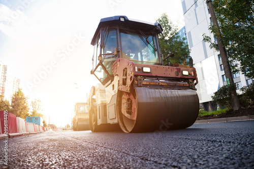 Photos Road Roller Compacts Fresh Asphalt on a Sunny City Street During Urban Paving Wo