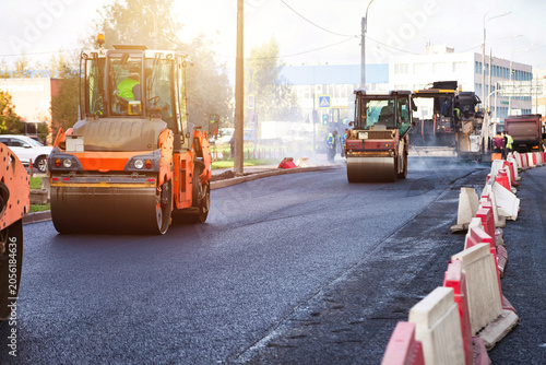 Urban Road Resurfacing Project With Heavy Machinery and Crew Compacting Fresh Asphalt