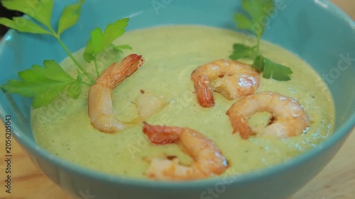 Presenting broccoli cream soup with shrimp and fresh herbs