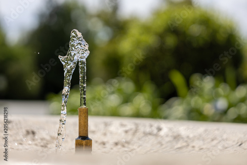 Fresh drinking water flowing from public fountain in city park, urban cooling and climate resilience concept during extreme summer heat with copy space