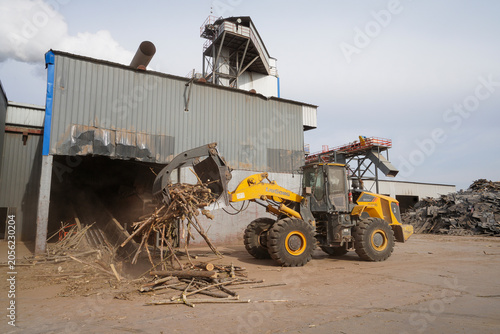 Workers drive engineering vehicles to transport branches in a sawdust processing plant, Luannan County, Hebei Province, China