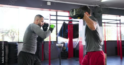 Trainer raising focus mitts urging boxer trainee throwing jab-cross combos for skill at boxing ring
