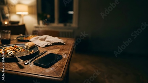smartphone on dining table beside unfinished meal illustrating digital distraction during dinner and screen addiction lifestyle concept