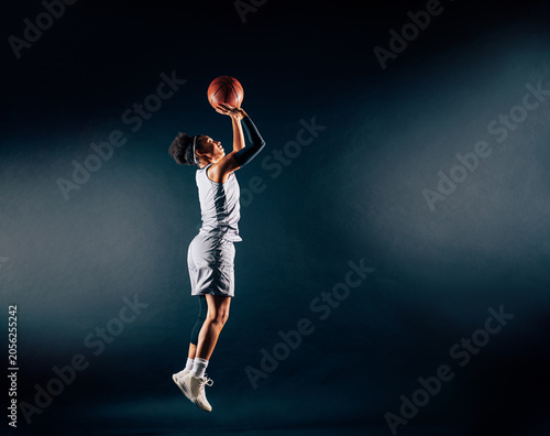 Full length of a basketball woman throwing a ball up in the studio