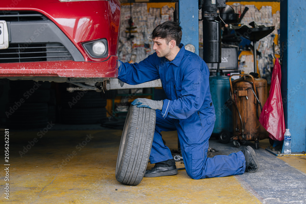 Fototapeta premium Auto mechanic worker changing car tire in auto workshop garage, Vehicle tyre maintenance service