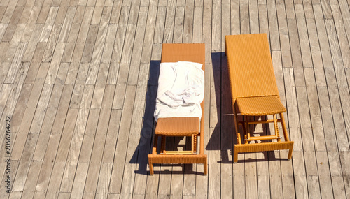 Bild auf Leinwand High-angle view of two rattan sunbeds on a wooden deck under bright sunlight