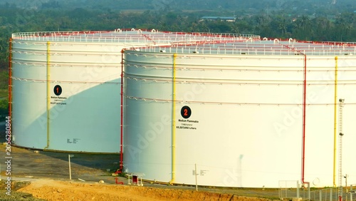 Photography Close aerial view of large oil storage tanks with access stairways and safety barriers, representing industrial monitoring, logistics efficiency, energy infrastructure, and reserve management