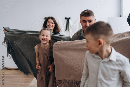Happy family enjoying quality time playing with blankets indoors