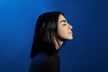 Young woman with eyes closed against blue background