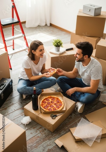 Happy Young Couple Eating Pizza and Drinking Wine While Taking a Break from Moving into Their New Home