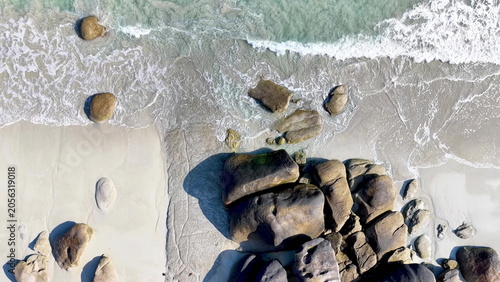 Spektakuläre Drohnenaufnahme vom Plage de Boutrouilles: Wellen treffen auf feinen Sandstrand und imposante, runde Granitfelsen an der wilden Küste der bretonischen Region.