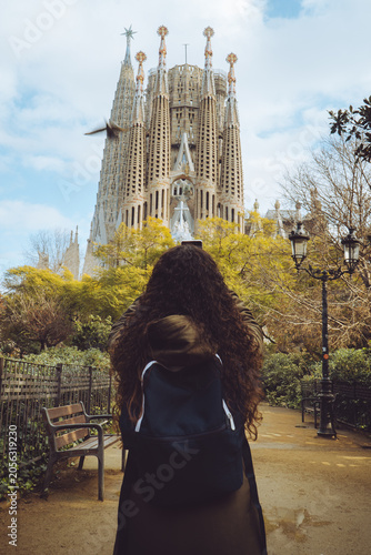 La Sagrada Familia, Barcelona, Spain, A woman with a backpack takes a photo of the iconic, towering spires of Antoni Gaudi's historic masterpiece.