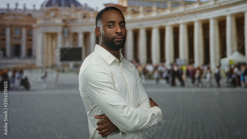 Obraz na płótnie Man standing with arms crossed, hands visible and clasped, in front of the vatican colonnade building and busy square plaza; confidence resolve faith