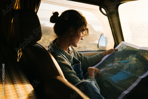 Woman studies map in car during sunset road trip