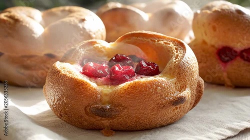 Close view of airy cherry popover with baked fruit and creamy custard center, golden crust on soft linen in morning backlight, appetizing pastry scene for popover day breakfast, warm bakery glow