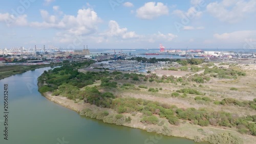 Aerial scenic view of the Kishon River park and Shavit Marina in Haifa, Israel, with the industrial cargo port and red cranes visible in the background.
