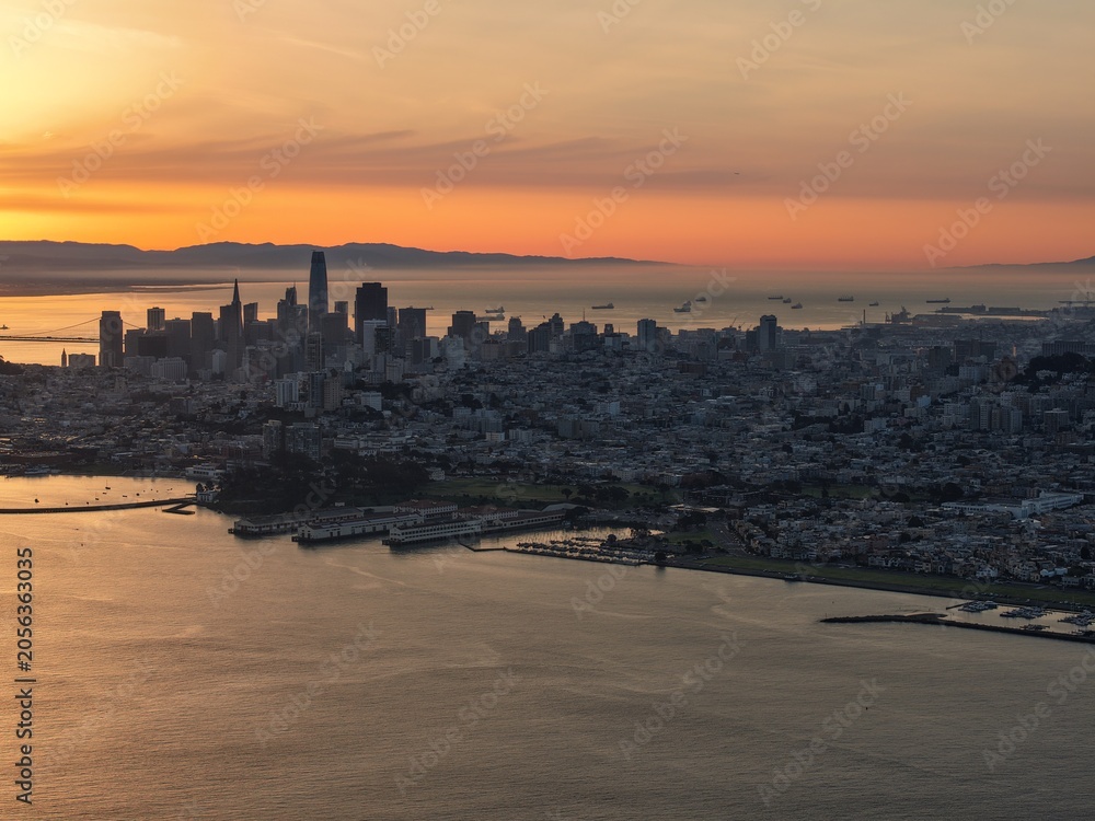 Fototapeta premium Golden sunset over San Francisco skyline with Bay Bridge and glowing bay waters. g.
