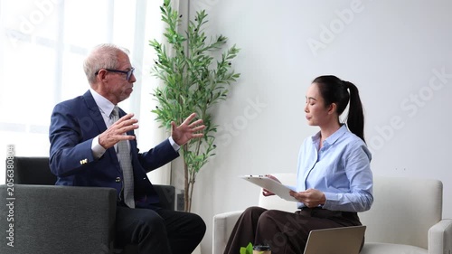 Senior businessman discussing project with asian businesswoman analyzing financial charts, corporate partners planning strategy and investment in a modern office meeting