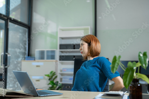 Businesswoman doing stretching pose due to sitting in office for too long, office syndrome concept.