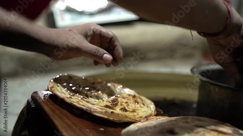 Close up shot of butter being applied on freshly cooked tandoori roti.