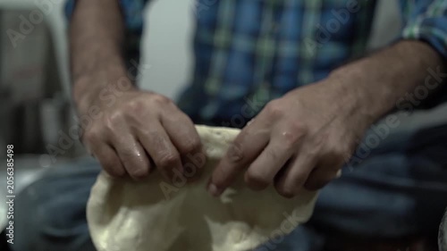 Hands kneading dough for making flaky laccha paratha during food preparation.