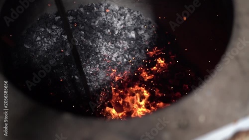 Cinematic shot of glowing coal fire burning inside traditional tandoor oven.