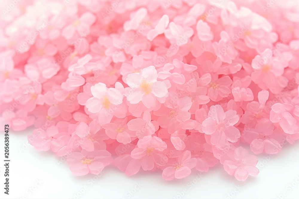 Obraz premium Soft pile of pink flower petals on a white background, creating a gentle spring floral texture with a delicate romantic feel.