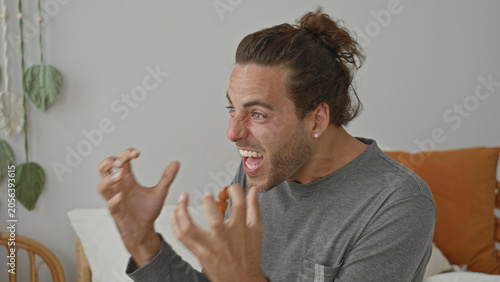 Fotografie Man on bed shouting with clawing hands and clenched fists in building, motion blur, visible pillow and hanging plant; anger outburst
