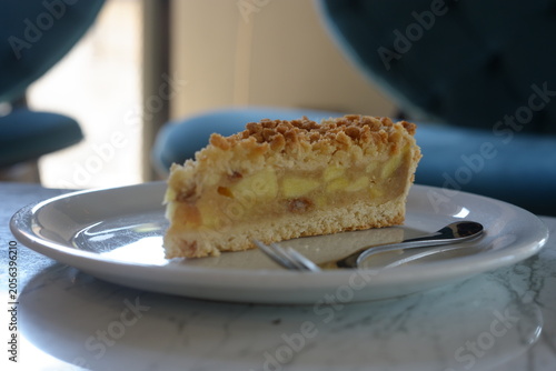 A slice of delicious homemade apple crumble pie served on a white plate in a cafe