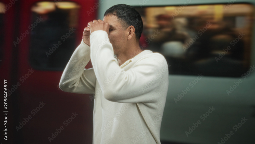 Obraz premium Man smiling with hands raised near train doors in a building, wearing a white polo and standing on a platform; contentment connection openness.