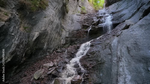 Water cascades down a rocky mountain stream in a lush green forest.