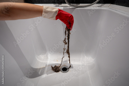 Konstfotografi Person cleaning shower drain from trapped hair and debris to restore proper water flow