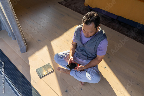 Smartphone is resting on pale wooden floor near sliding glass door with long shadows, copy space