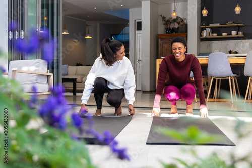 Foto Diverse female friends in workout gear placing black yoga mats on tiled threshol