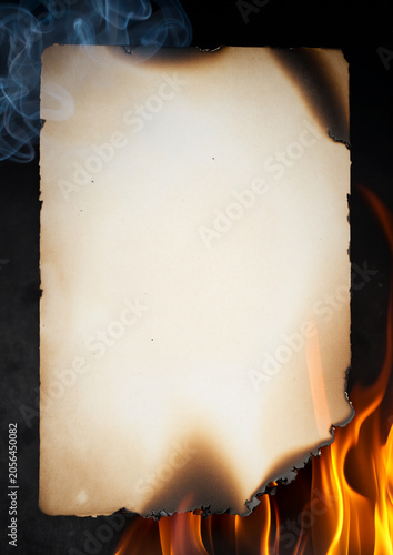 Burning paper sheet with flames, smoke and charred edges isolated on dark background
