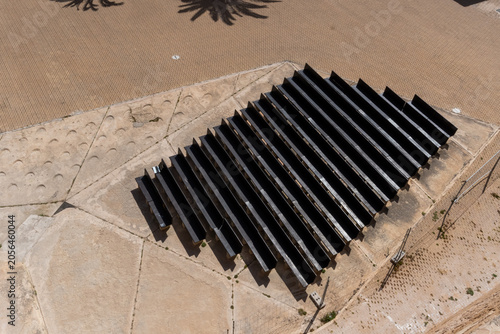 Tableau sur toile High angle view of rows of dark solar panels or parallel structures on a concrete installation in a sunny, arid or coastal landscape