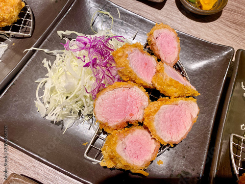 crispy japanese tonkatsu pork cutlet with shredded cabbage on dark plate top down view