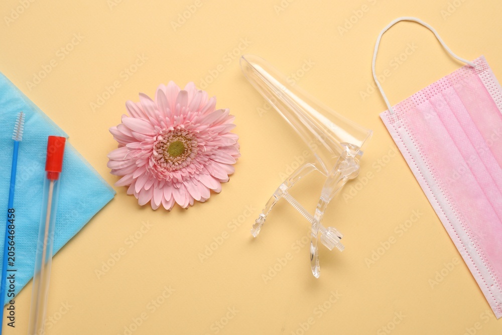 Obraz premium Flat lay composition with gynecological examination kit and gerbera flower on pale orange background