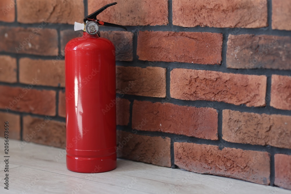 Fototapeta premium One red fire extinguisher on floor indoors, space for text
