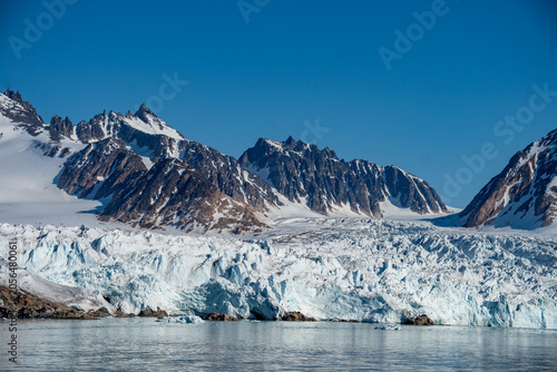 Bild auf Leinwand Glacier meeting the Arctic Ocean at the base of the mountains in Bjornfjorden, S